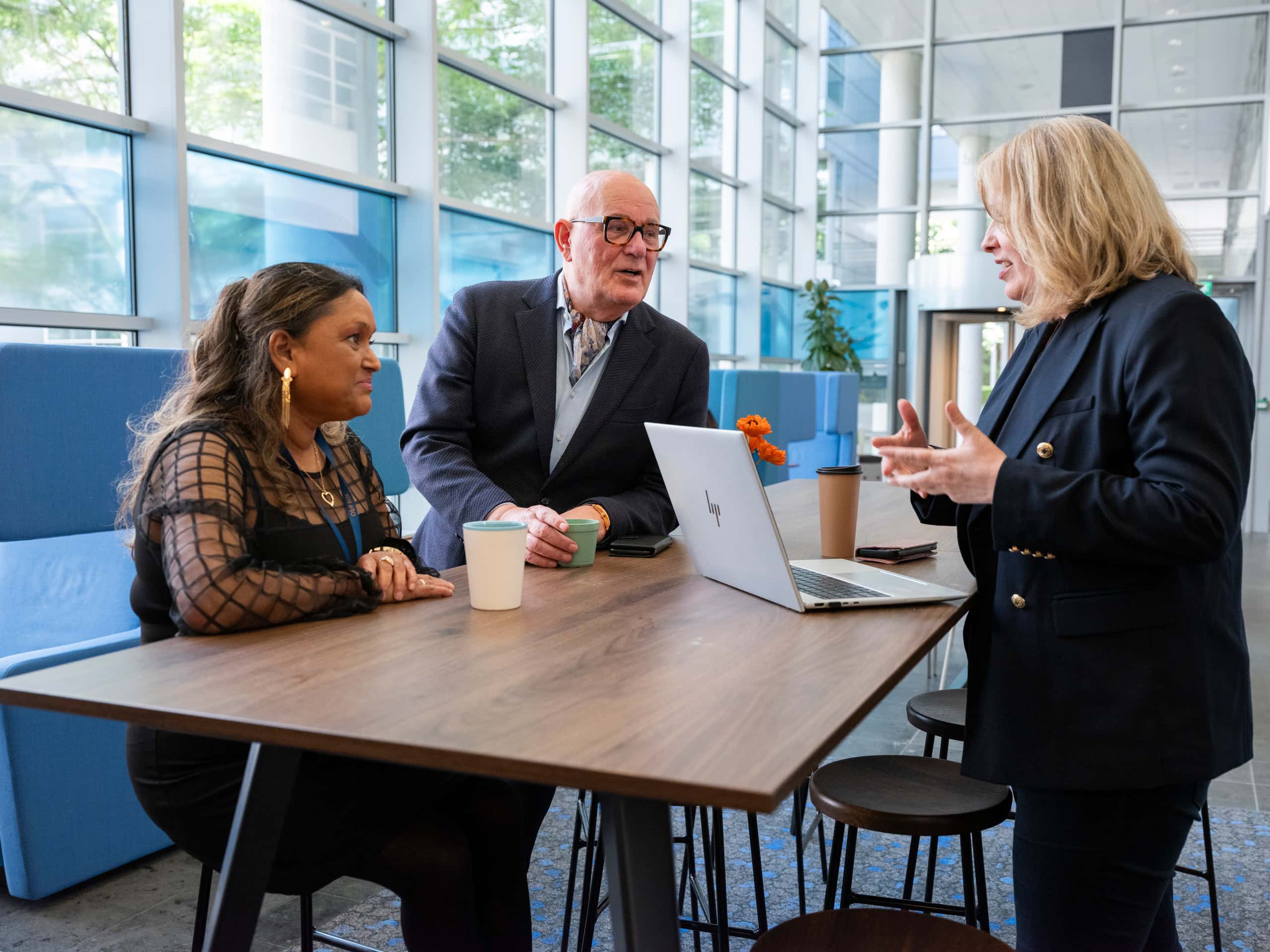 3 medewerkers zitten om tafel, in gesprek
