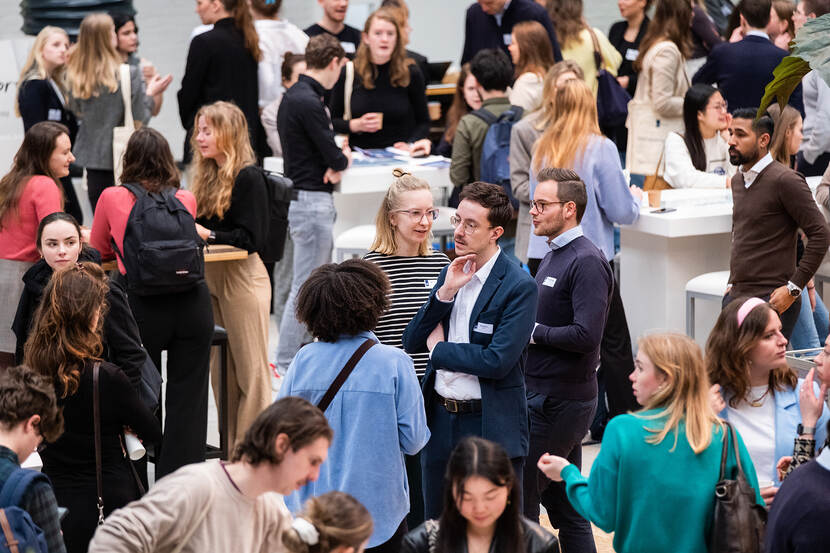 Grote groep afgestudeerden aan statafels bij Traineeplaza