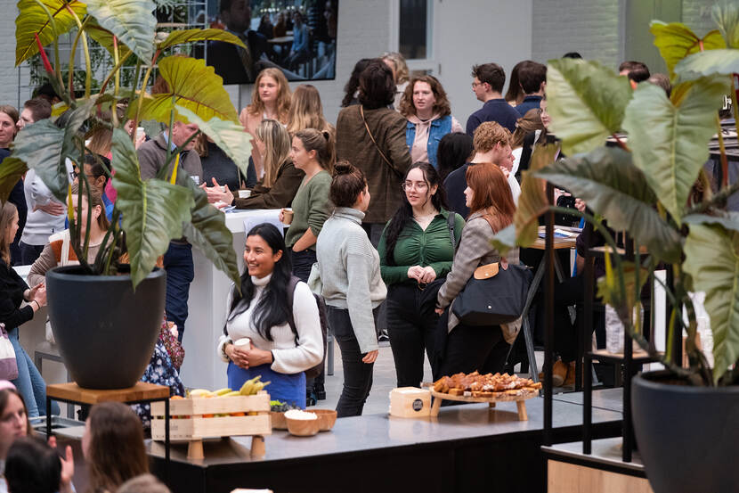 Grote groep afgestudeerden bij Traineeplaza, in open ruimte met planten en snacks