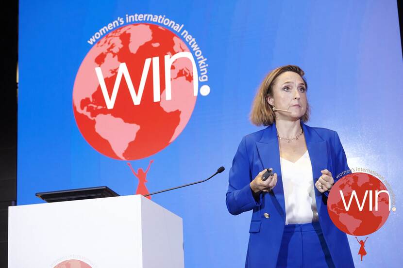 Wendelijn als spreker op een podium met het logo van women's international networking op de achtergrond
